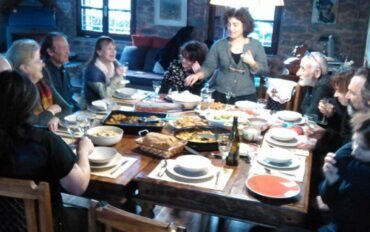 Ένα τραπέζι γεμάτο πιάτα με φαγητό καμμία παρέα που συζητάει